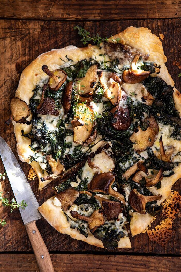 overhead photo of Roasted Mushroom Kale Pizza with slice cut and knife on board