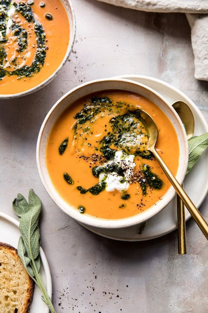 overhead photo of Golden Sweet Potato Soup with Burrata and Sage Pesto with spoon in bowl and bread on table