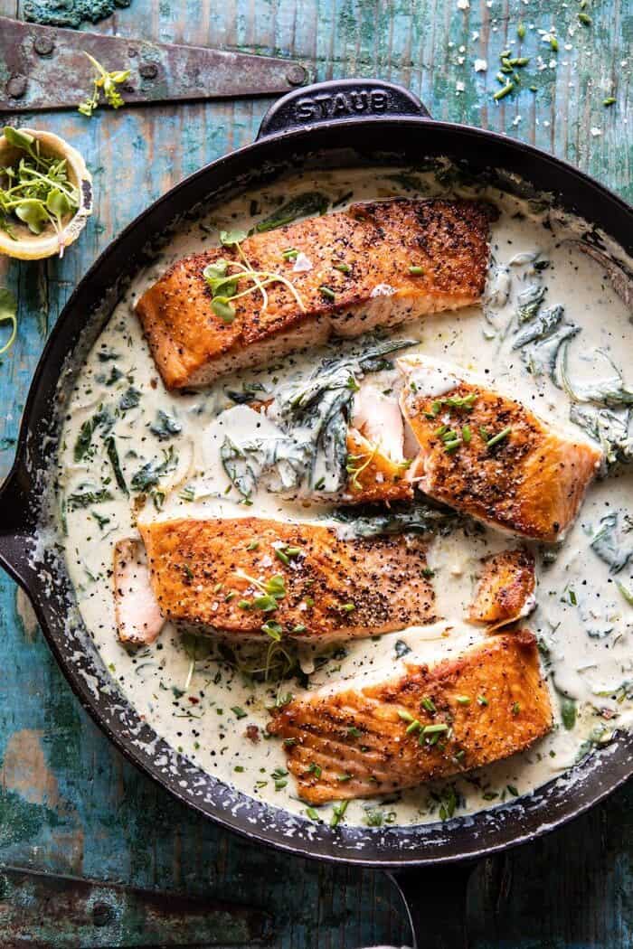 Garlic Butter Creamed Spinach Salmon in skillet with 1 salmon filet broken in half