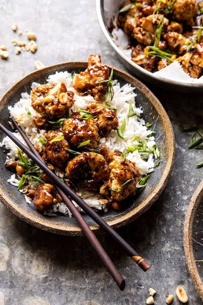 side angled close up photo of Better Than Takeout Kung Pao Cauliflower in a bowl with rice an chopsticks