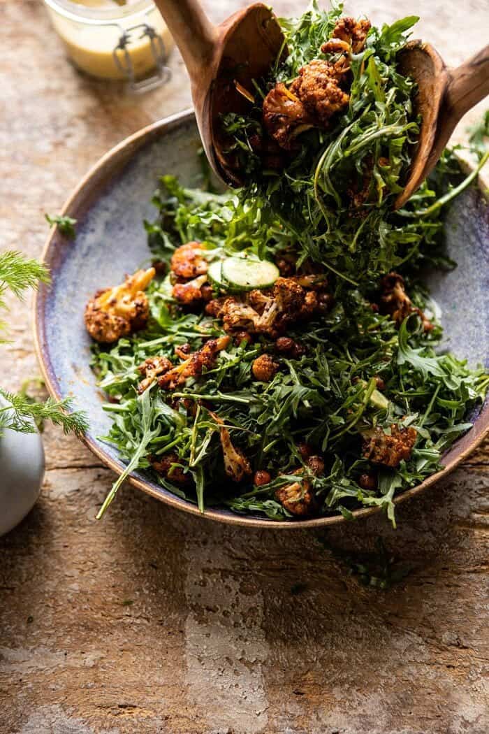 side angled photo of Roasted Cauliflower Salad with Creamy Honey Mustard Vinaigrette being tossed in salad bowl 