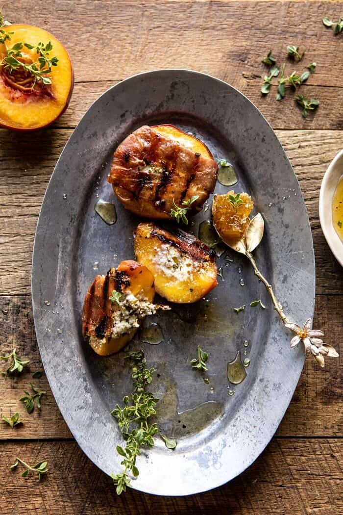 overhead photo of Prosciutto Goat Cheese Stuffed Peaches with Thyme Honey with peaches remove from platter and peach cut in half