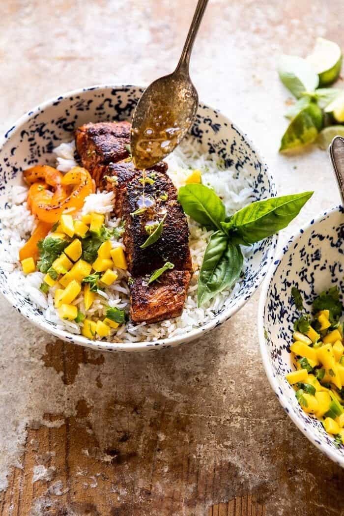 overhead photo of Cilantro Lime Salmon with Mango Salsa with chili lime butter being drizzled over top salmon