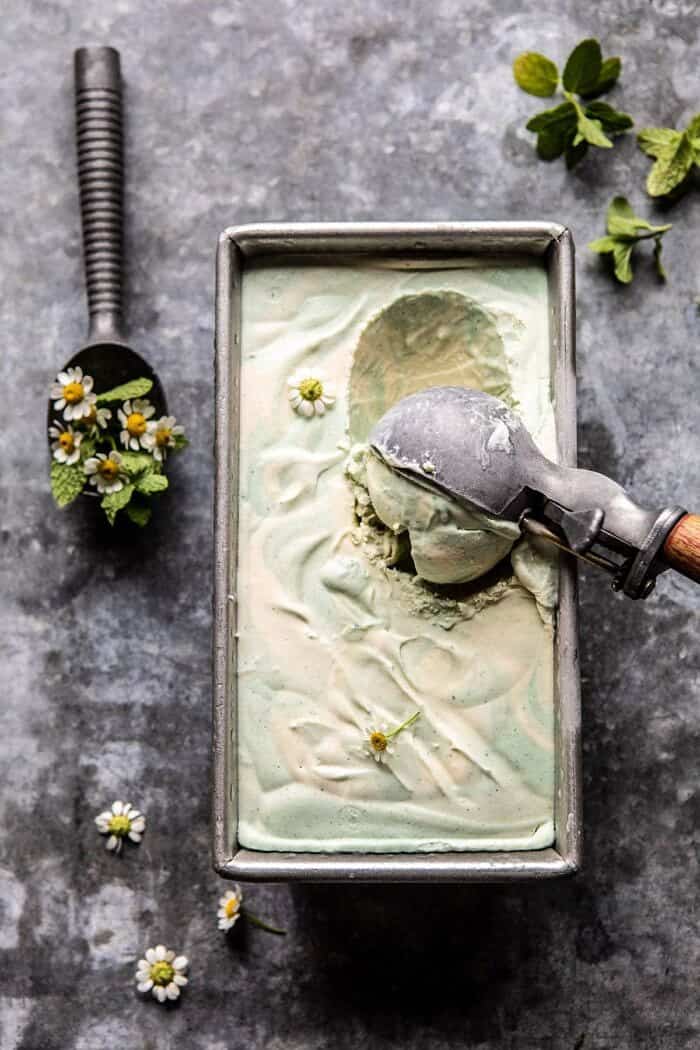 overhead photo of No Churn Minted White Chocolate Swirled Ice Cream with ice cream scoop in ice cream scooping out first scoop of ice cream