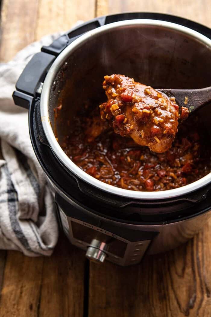 Healthier 30 Minute Beer Braised Chicken in instant pot with spoon picking chicken up out of instant pot