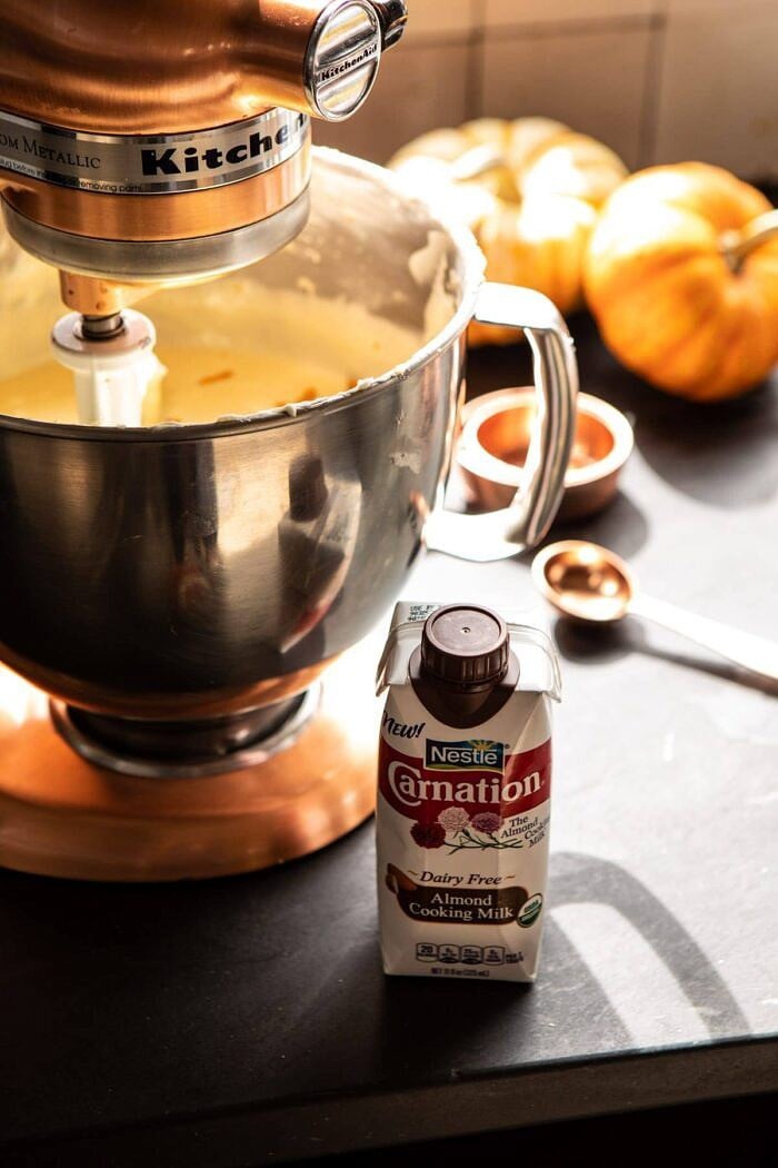 side angled photo of almond milk siting next to stand mixer 