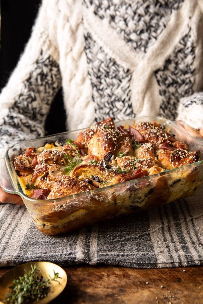side angled photo of Ham and Cheese Croissant Bake with someone holding the dish in the background