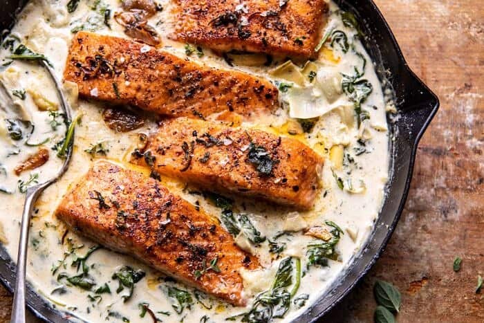 overhead horizontal photo of Creamy Spinach and Artichoke Salmon in skillet