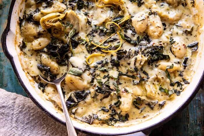 horizontal photo of Skillet Baked Creamy Pesto Spinach and Artichoke Gnocchi