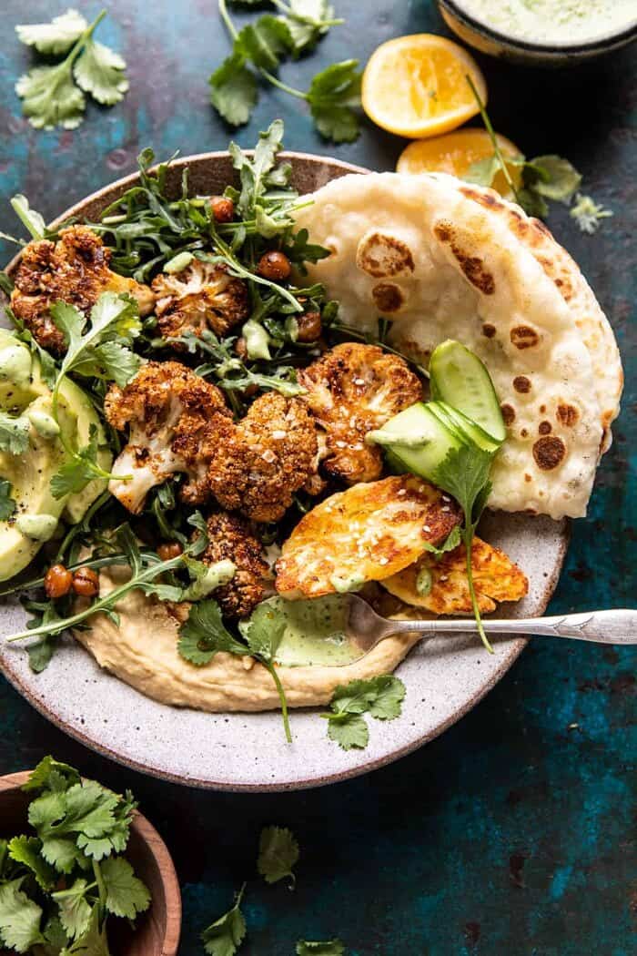 overhead photo of Cauliflower Shawarma with Green Tahini and Fried Halloumi and spoon full of green tahini in bowl 