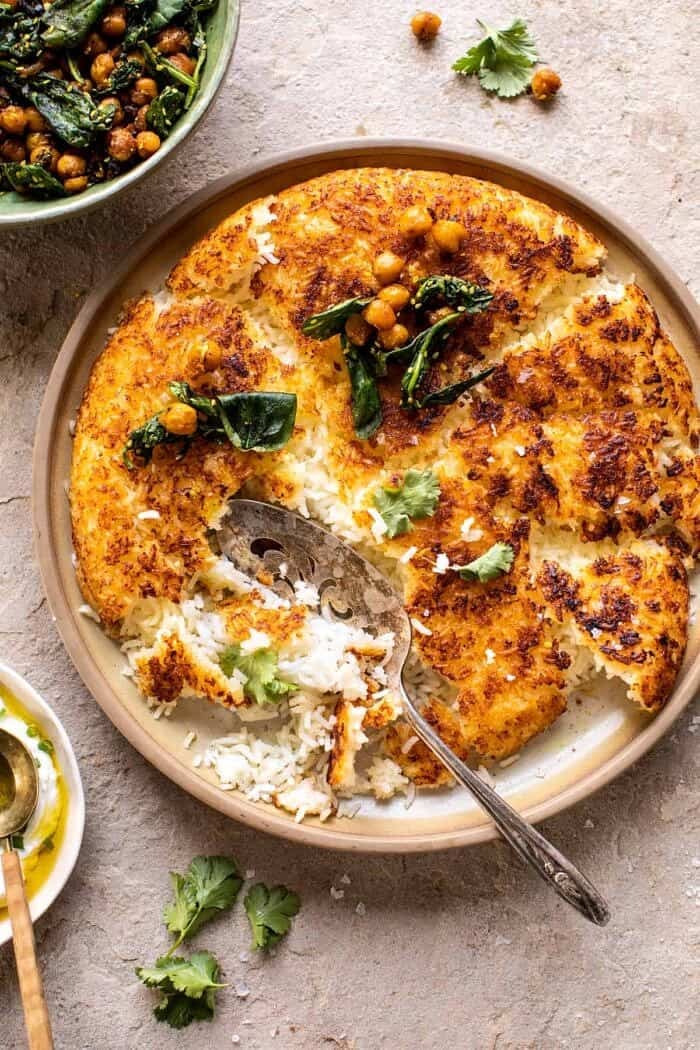 overhead photo of Crispy Persian Rice (Tahdig) with Spiced Golden Chickpeas with spoon in rice