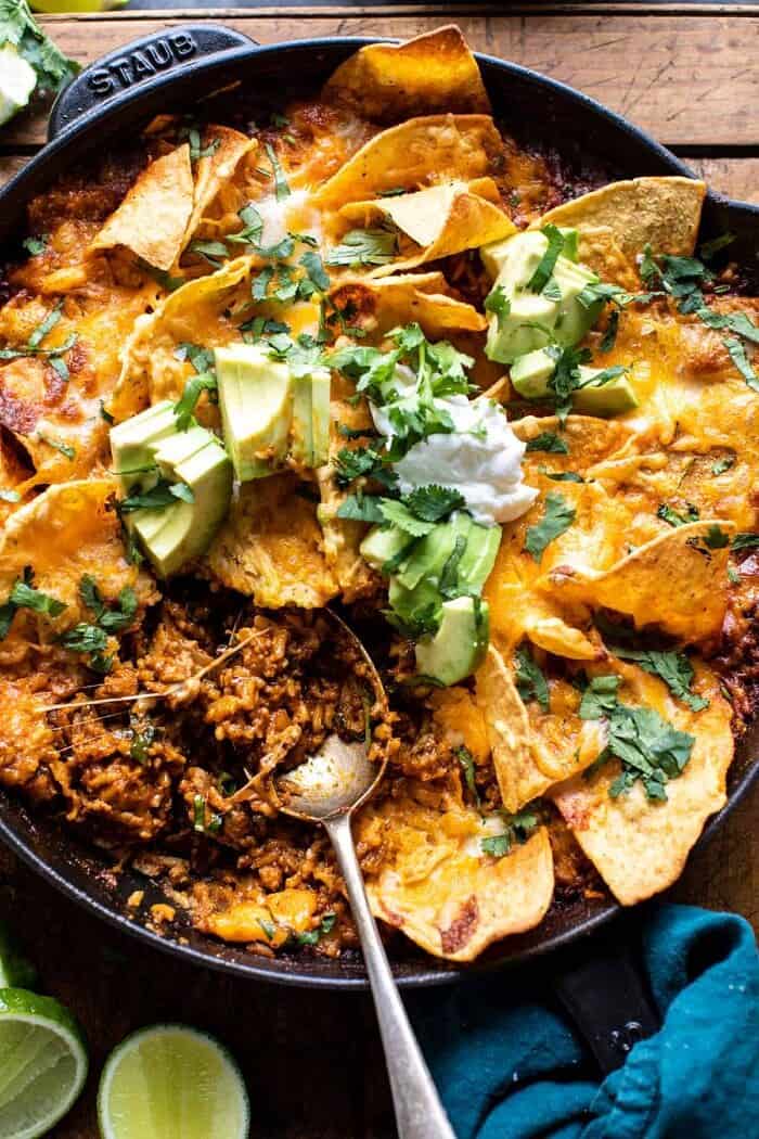 photo of One Skillet Saucy Chicken Tortilla Enchilada Rice Bake with spoon in skillet pulling up the rice to serve
