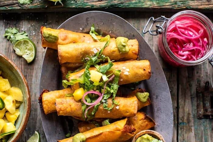 overhead horizontal photo of Crispy Chicken Tinga Taquitos with Salty Lime Avocado Crema