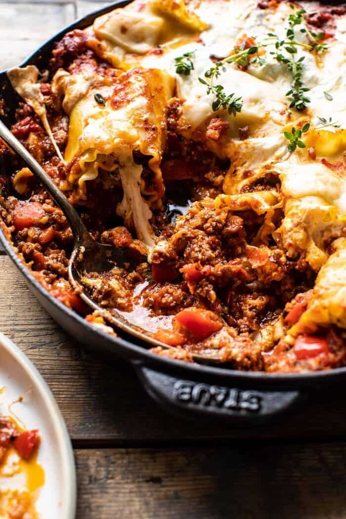 side angled photo of Simple Skillet Pesto Cheese Lasagna Roll Ups with spoon in skillet 