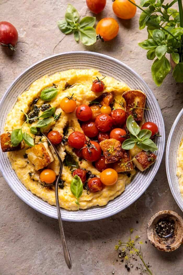 overhead photo of Cherry Tomato Pesto Polenta with Fried Halloumi and fork in serving bowl