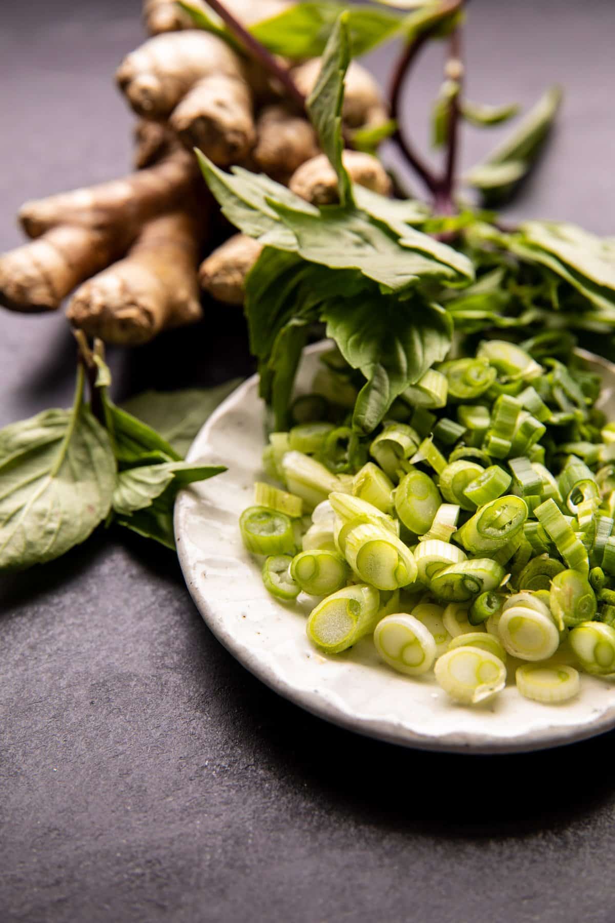 photo of green onions on plate with ginger and baisil