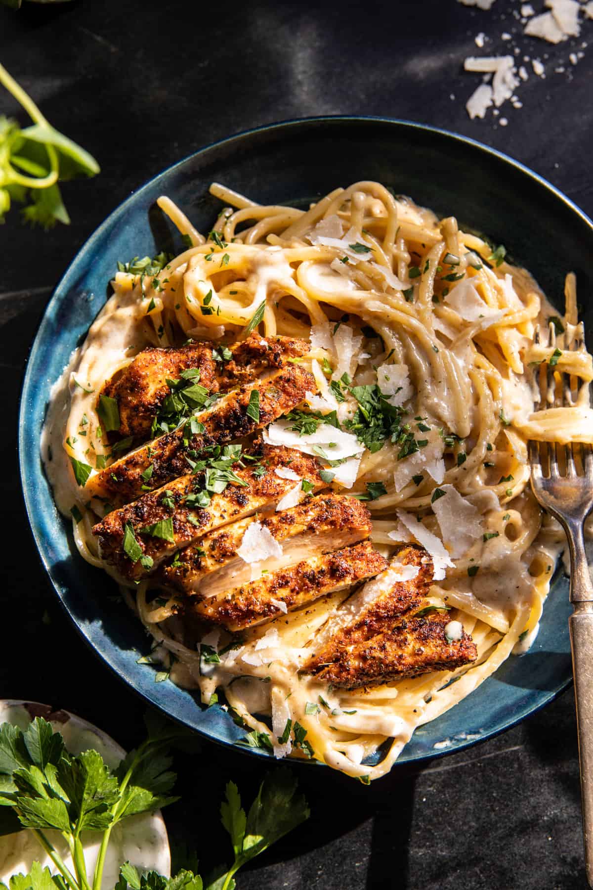 overhead photo of pasta and chicken in a pasta bowl with a fork and herbs