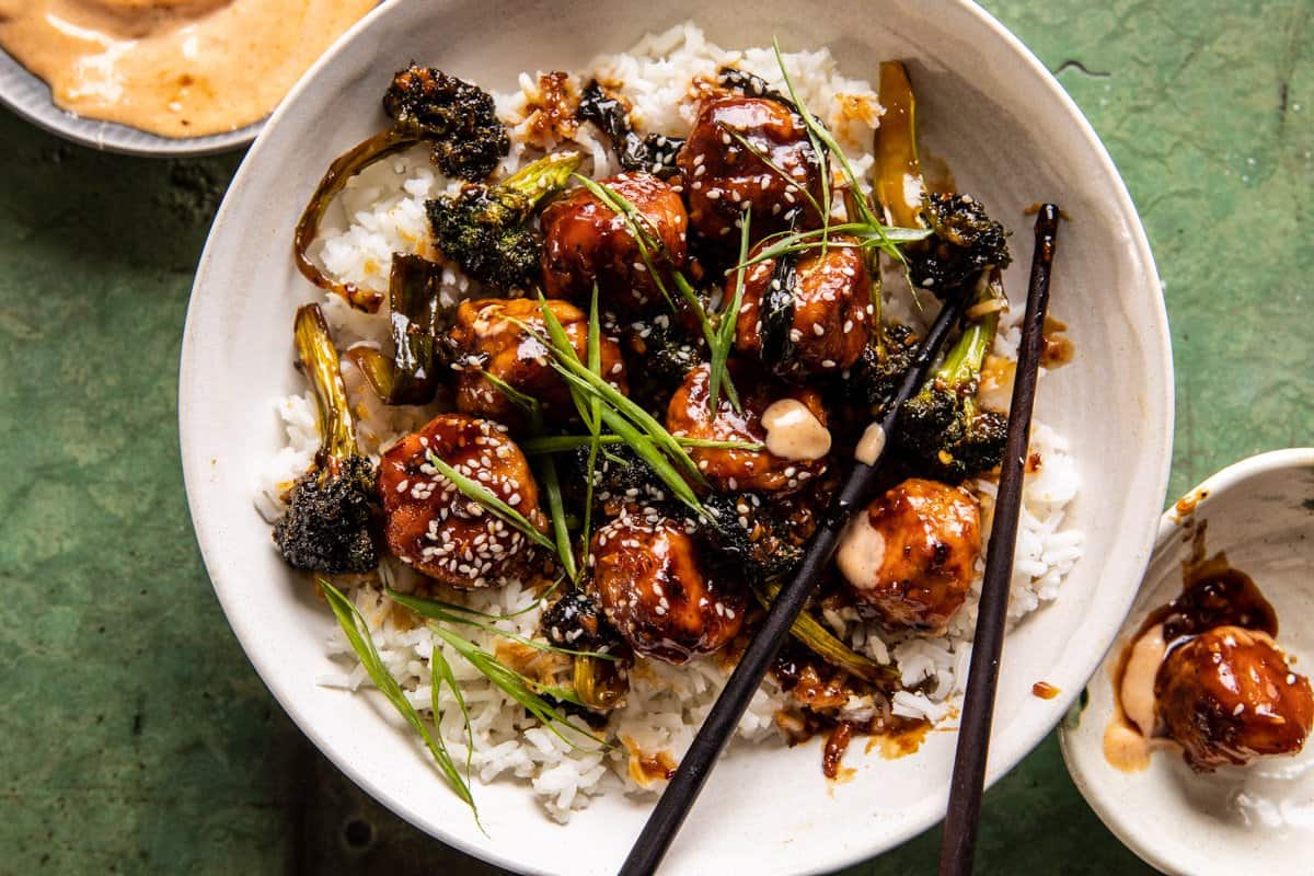 photo of meatballs in bowl with rice and chopsticks and sauce on table 