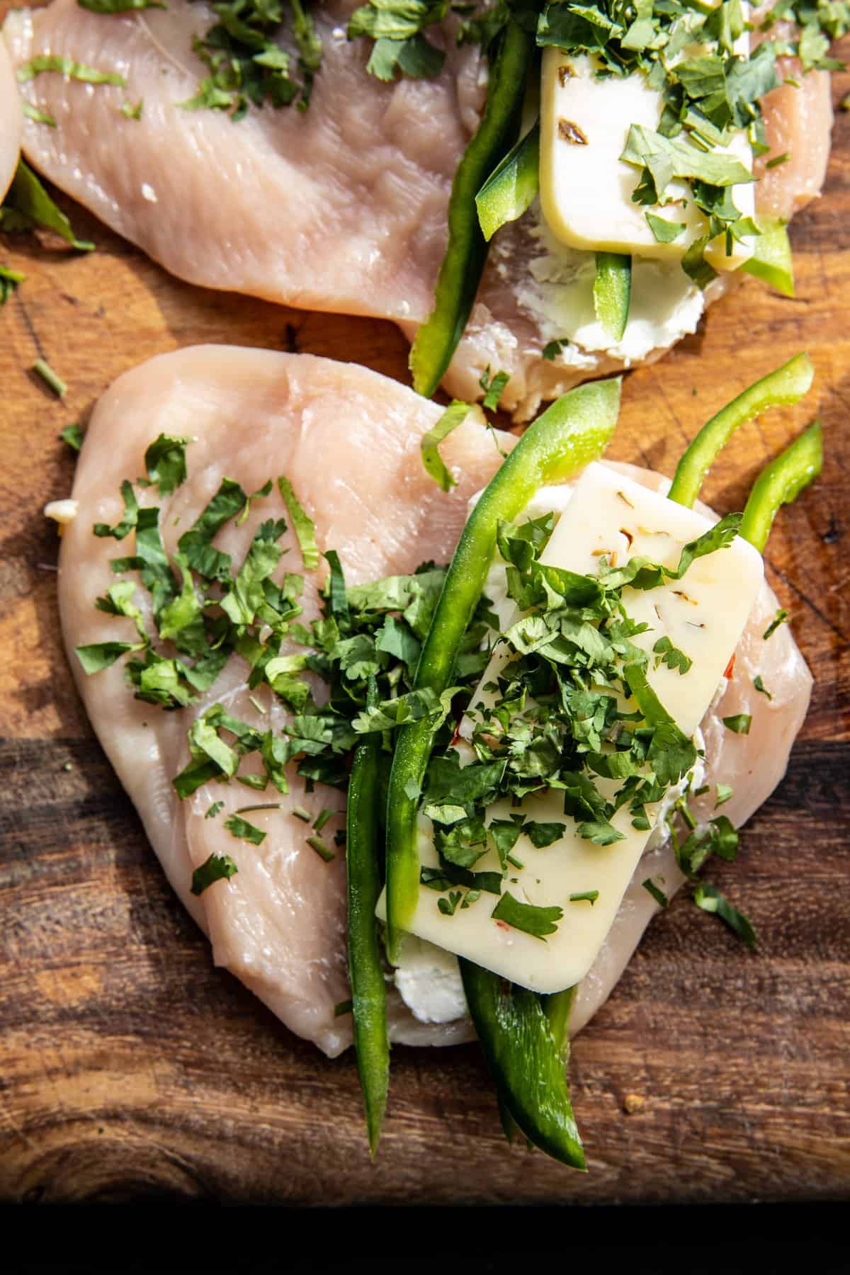 prep photo of raw chicken filled with cheese and peppers 