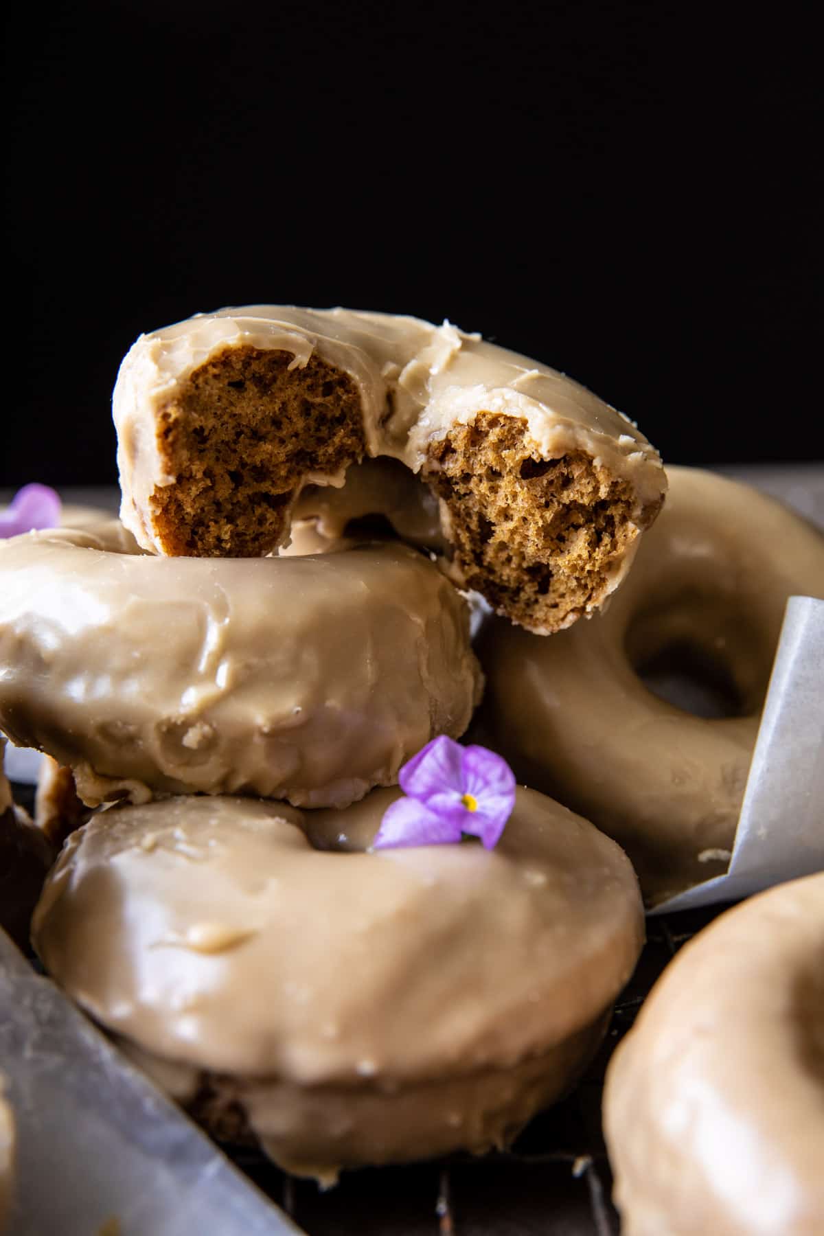 side angled photo of half eaten doughnut stacked on other doughnuts 